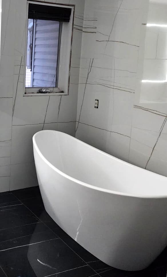 Bain autoportant blanc devant un mur de grands carreaux veinés